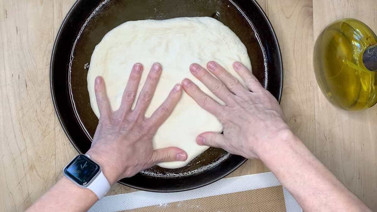 stretching the dough inside the pan.