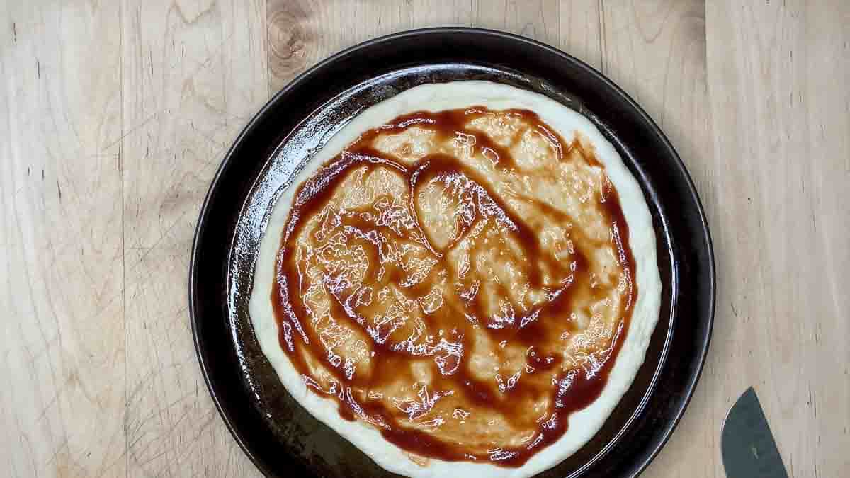 adding sauce to the crust.