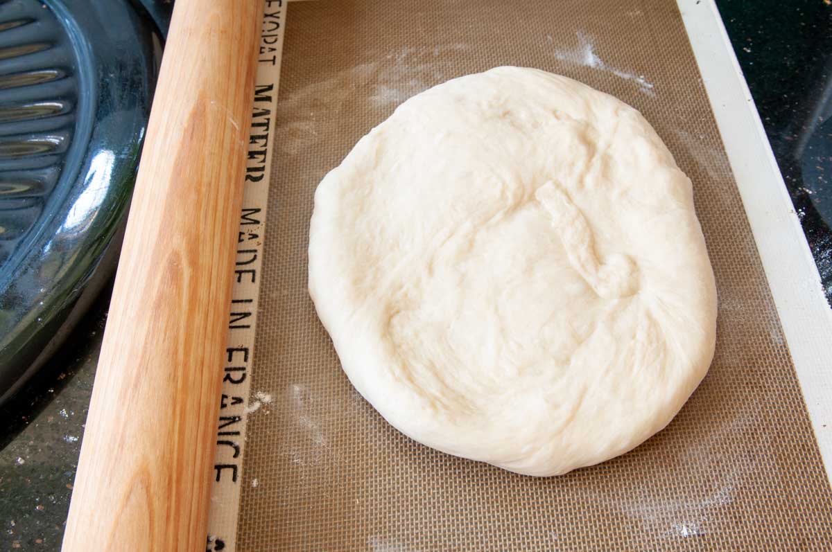 Shaping dough into a rough circle.