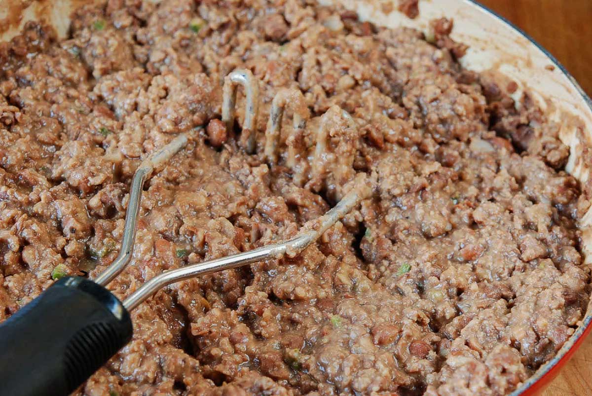 mashing beans and beef together.