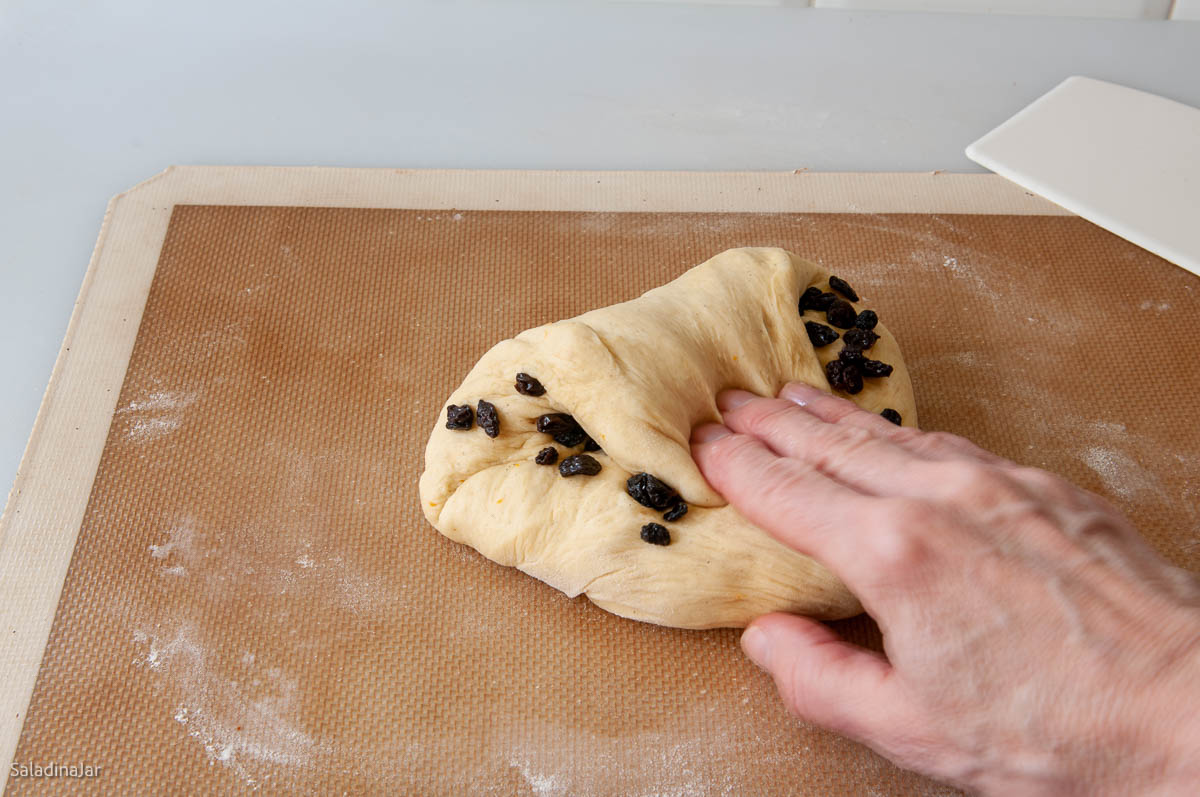kneading raisins into dough by hand