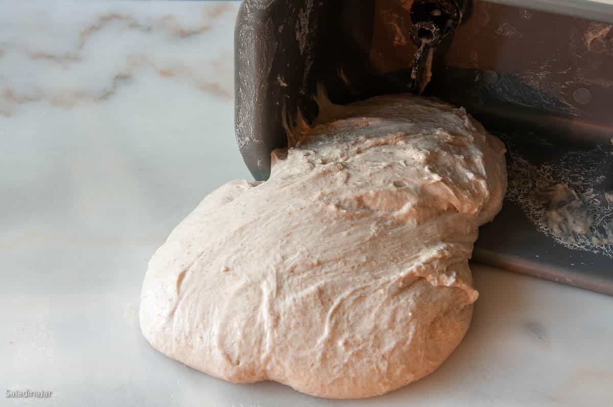 pulling dough out of the pan onto the marble.