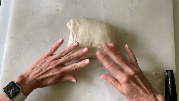 gently pushing on the dough to create tension