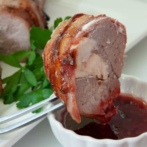 slice of wrapped tenderloin being dipped in sauce