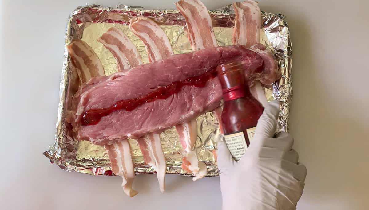 pouring raspberry sauce over split meat