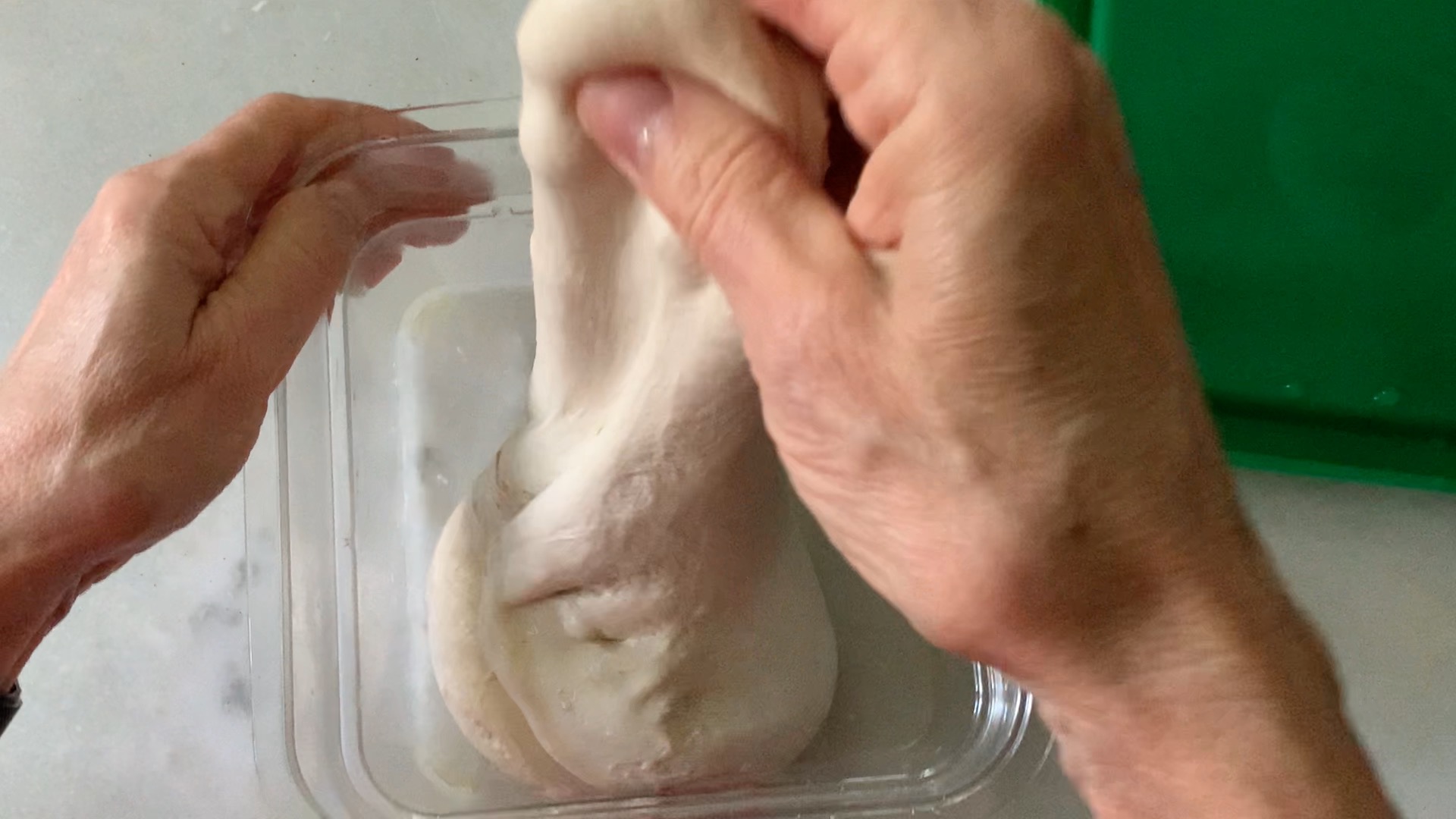 Stretching and folding the dough in the container at the beginning of bulk rise.