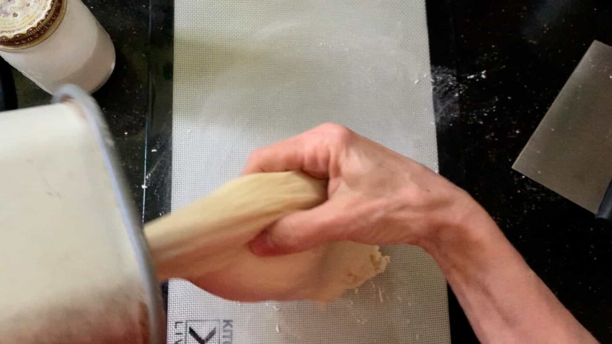 pulling the dough out of the machine at the end of the DOUGH cycle.