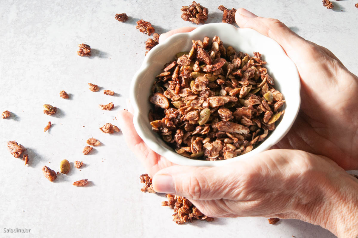 two hands holding a bowl of granola