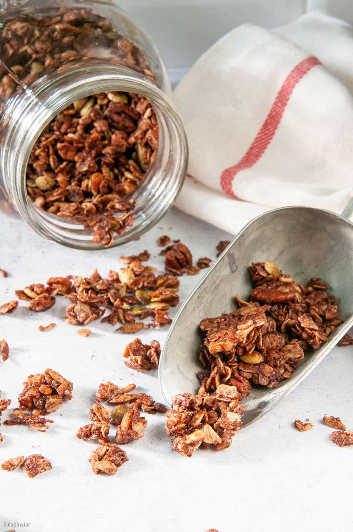 Ready-to-eat Chocolate Granola spilling out of a jar.
