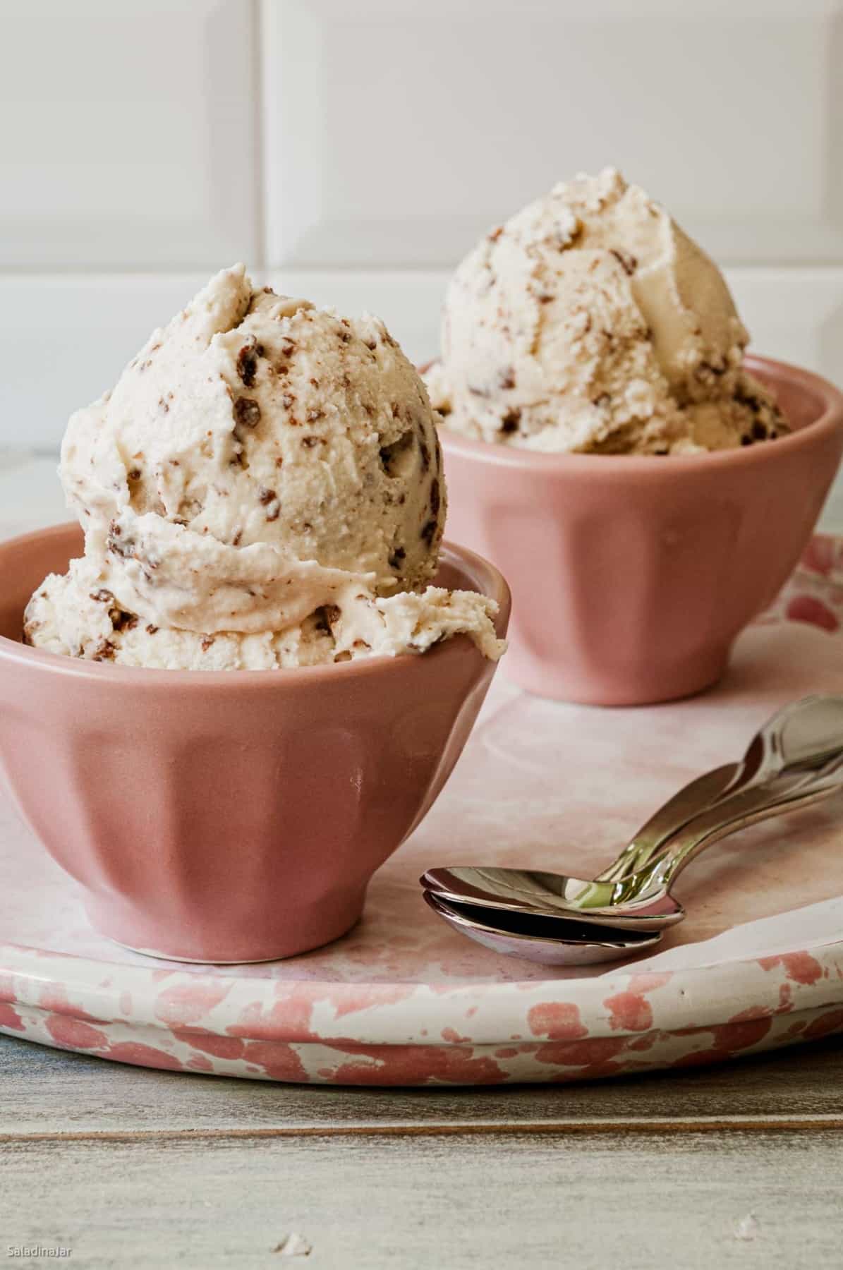 scoops of creme fraiche ice cream with Nutella flakes in pink bowls.
