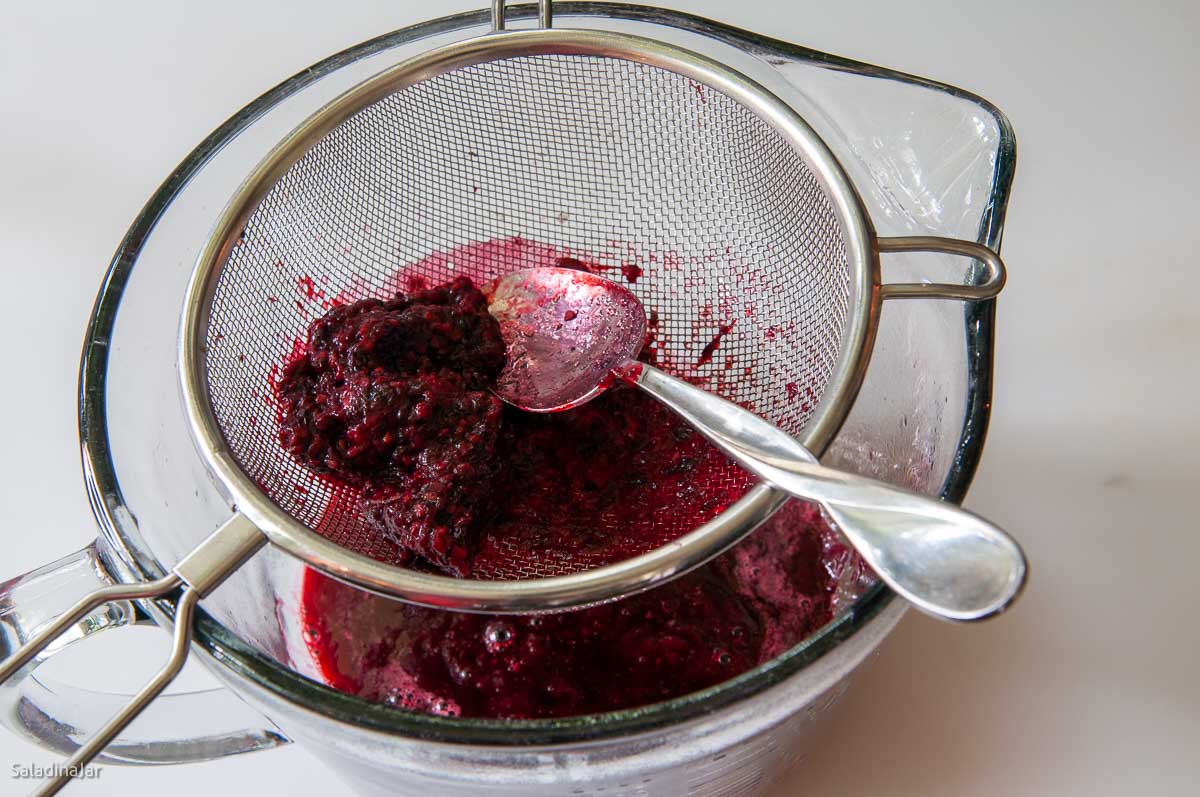 forcing berries through a strainer