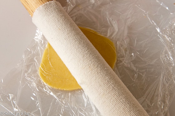 Flattening the disc of dough with a rolling pin.