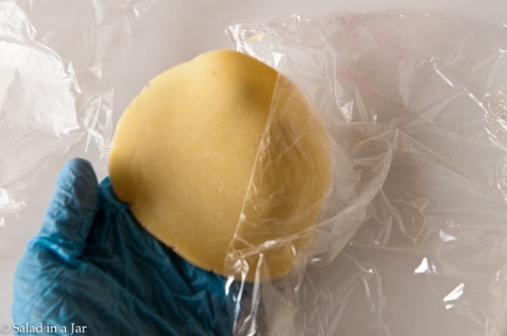 Pulling the plastic wrap from each side of the dough.