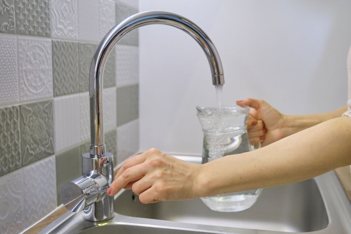 woman filling a pitcher with tap water