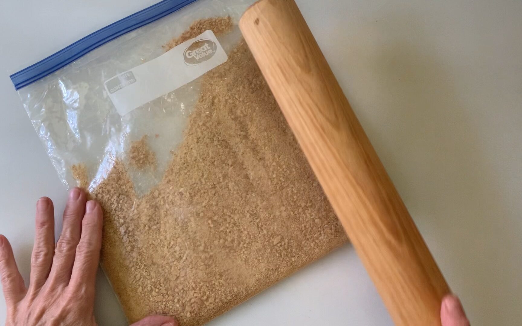 Using a rolling pin to crush the graham crackers.