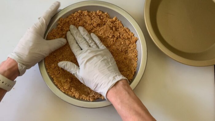 Using gloved hands to pat down crumbs