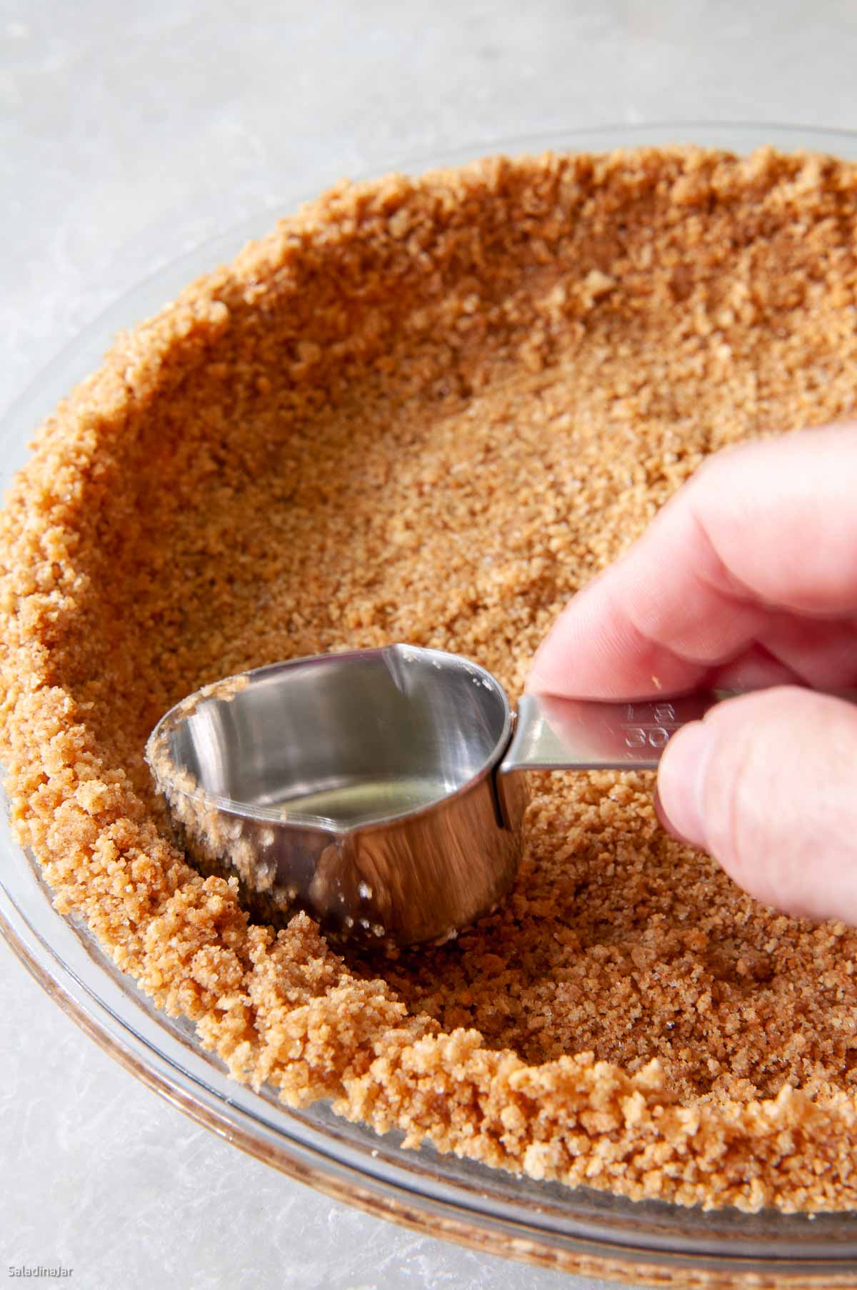 using a measuring cup to shape the crust