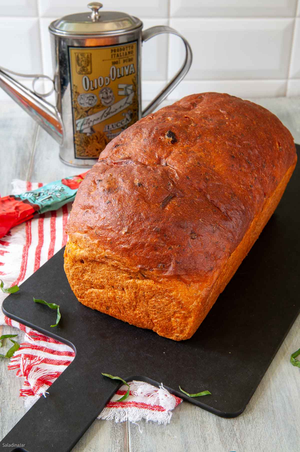 Uncut tomato basil bread on a cutting board