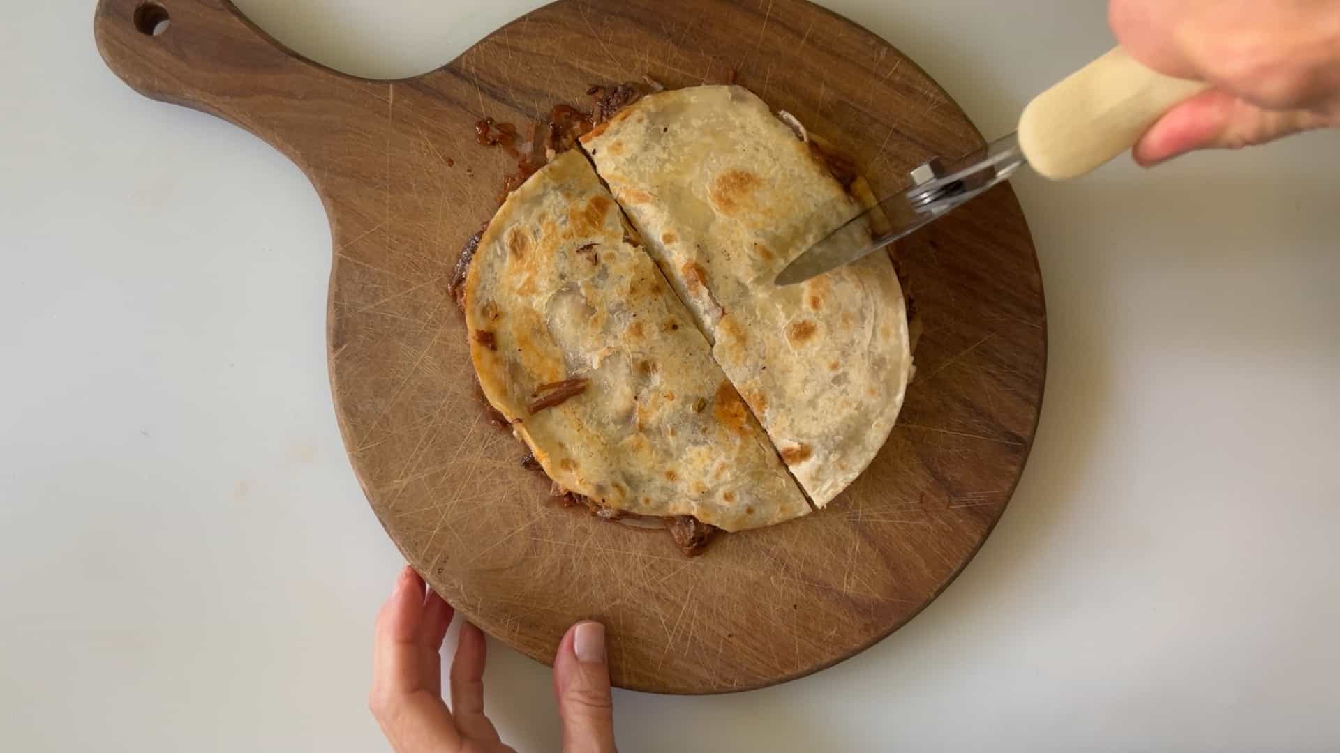 cutting baked tortilla with a pizza cutter.