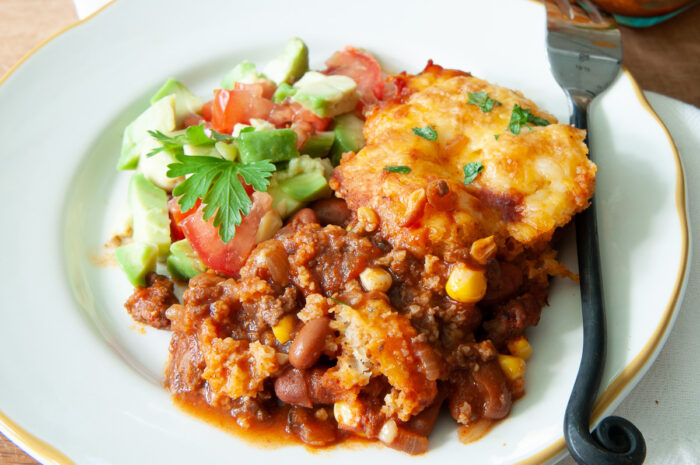 serving of tamale pie with avocados, tomatoes, and cilantro.