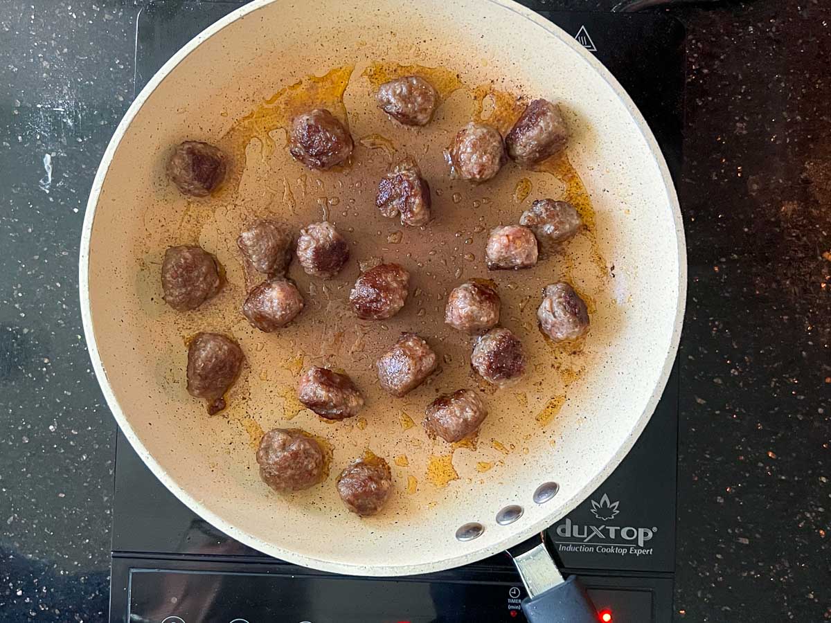 browning sausage meatballs in a skillet