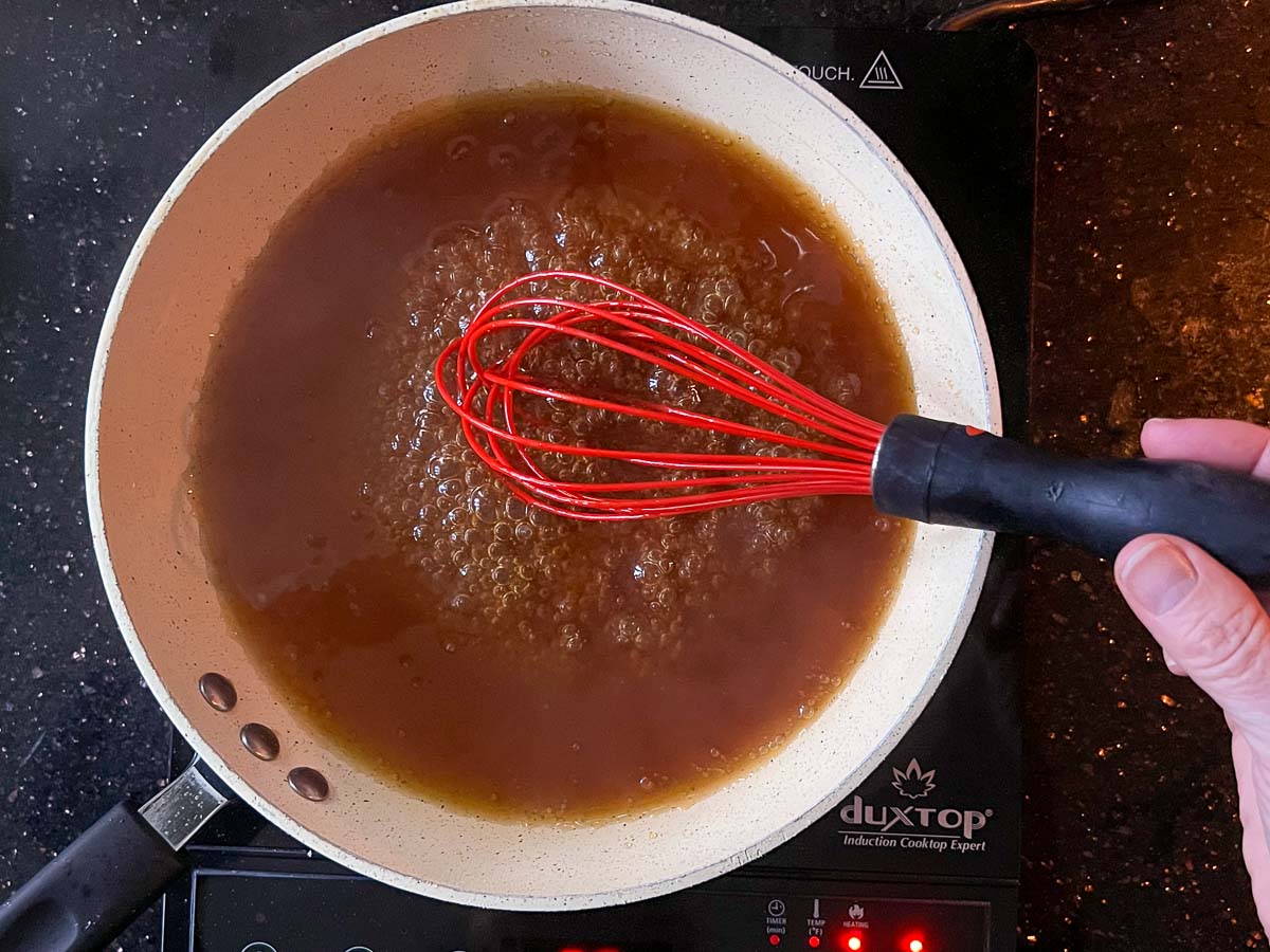 whisking sauce as it cooks in skillet