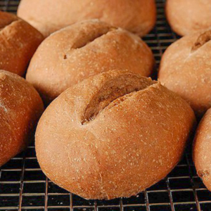 dark brown bread rolls on a cooling rack