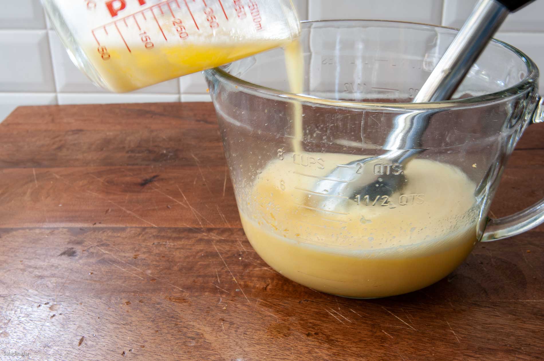 Adding hot butter to the egg mixture while using the immersion blender.