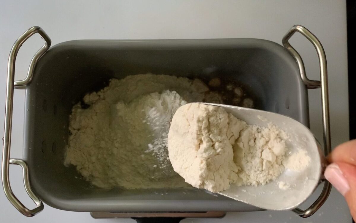 adding whole wheat and bread flour to water in pan 