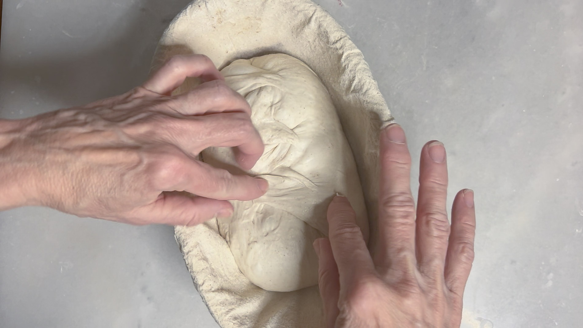 Stitching the dough with fingers to create tension
