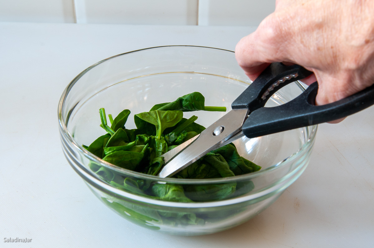 using kitchen shears to cut spinach.