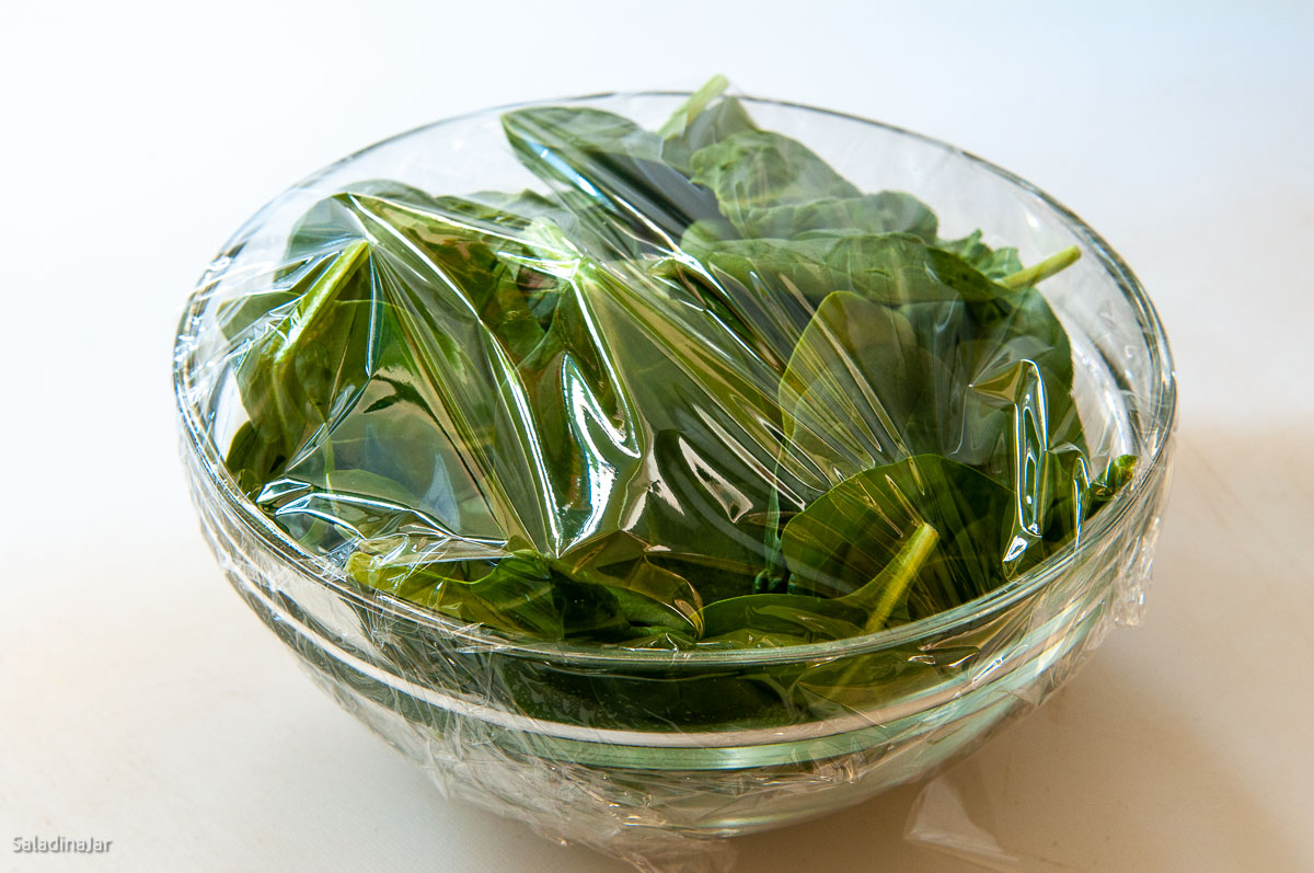 raw spinach in a bowl covered with cellophane.