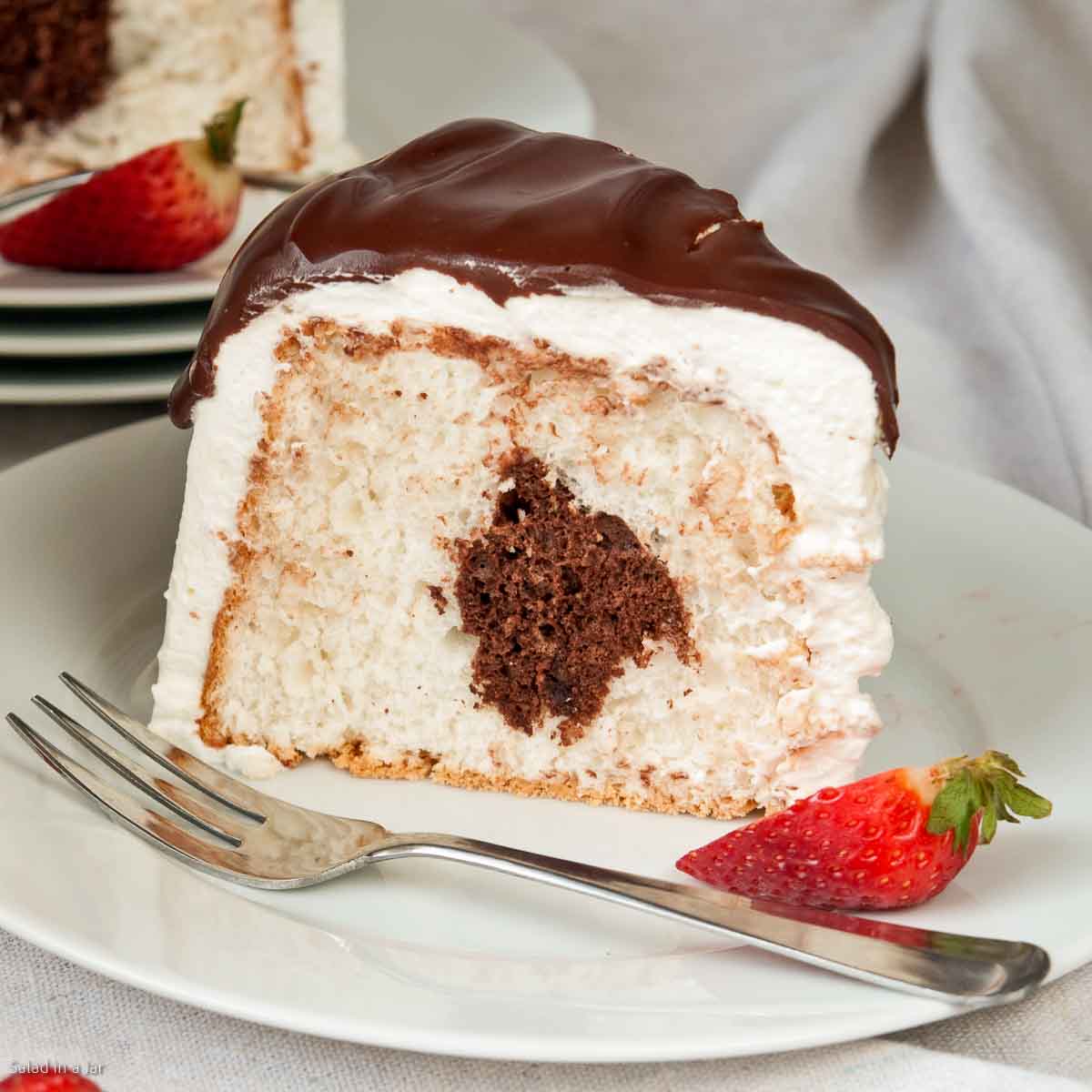 slice of cake showing the chocolate in the middle with a strawberry on the side.