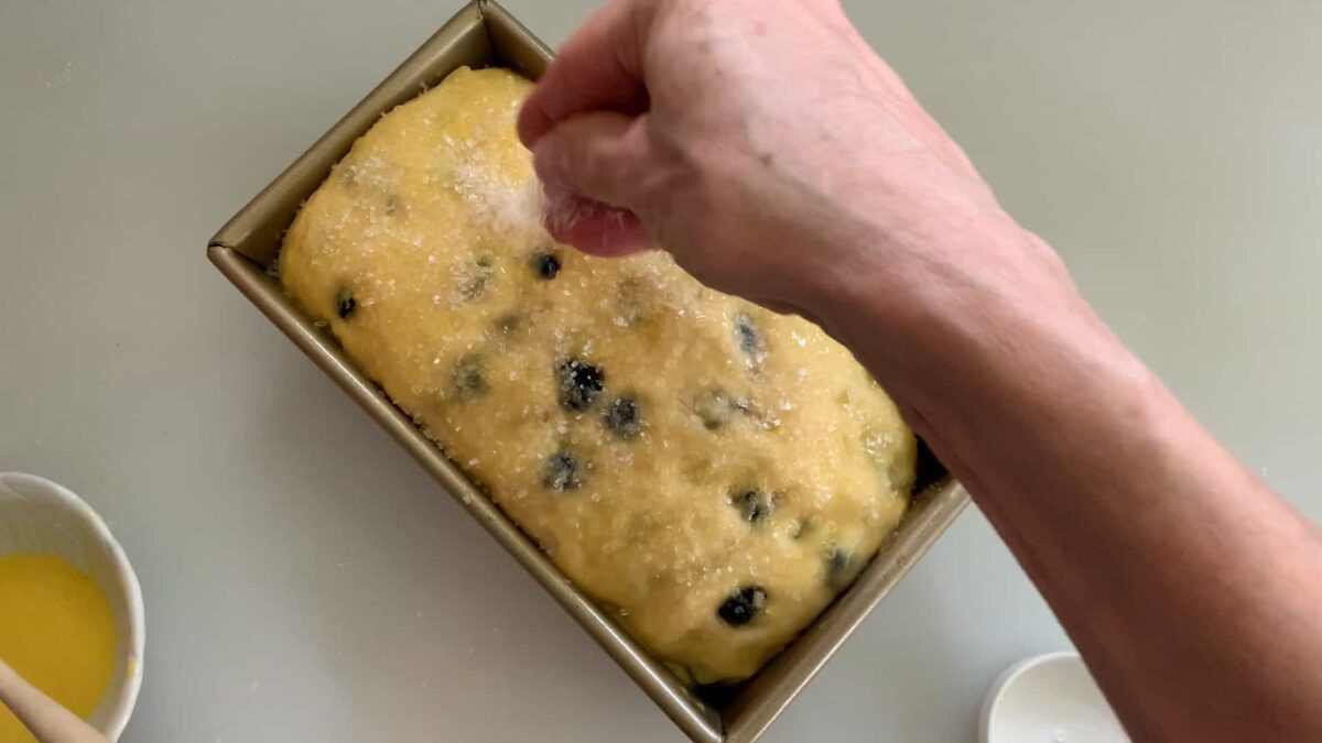 Sprinkling loaf with sugar.