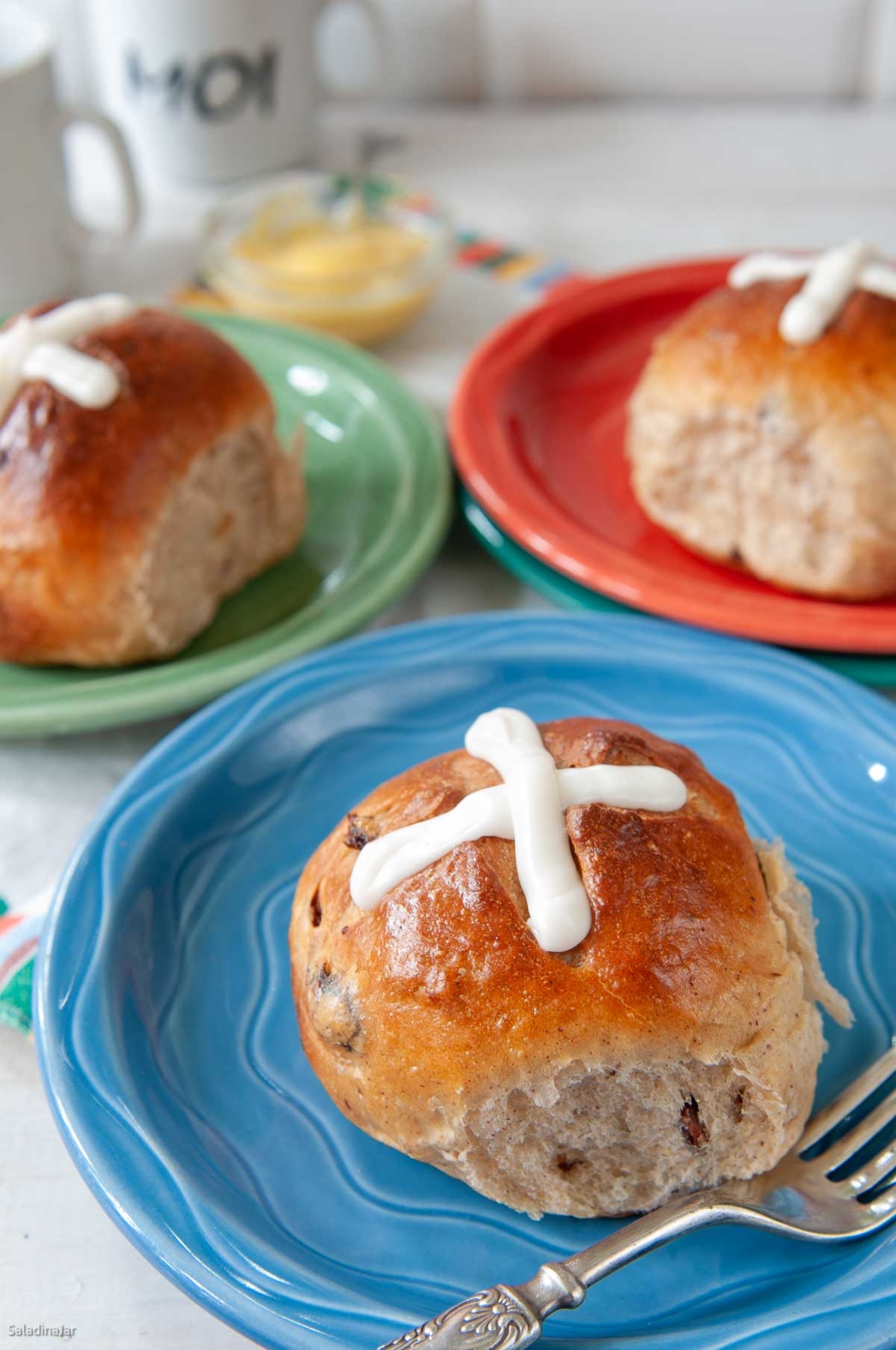 hot cross buns on brightly colored plates.