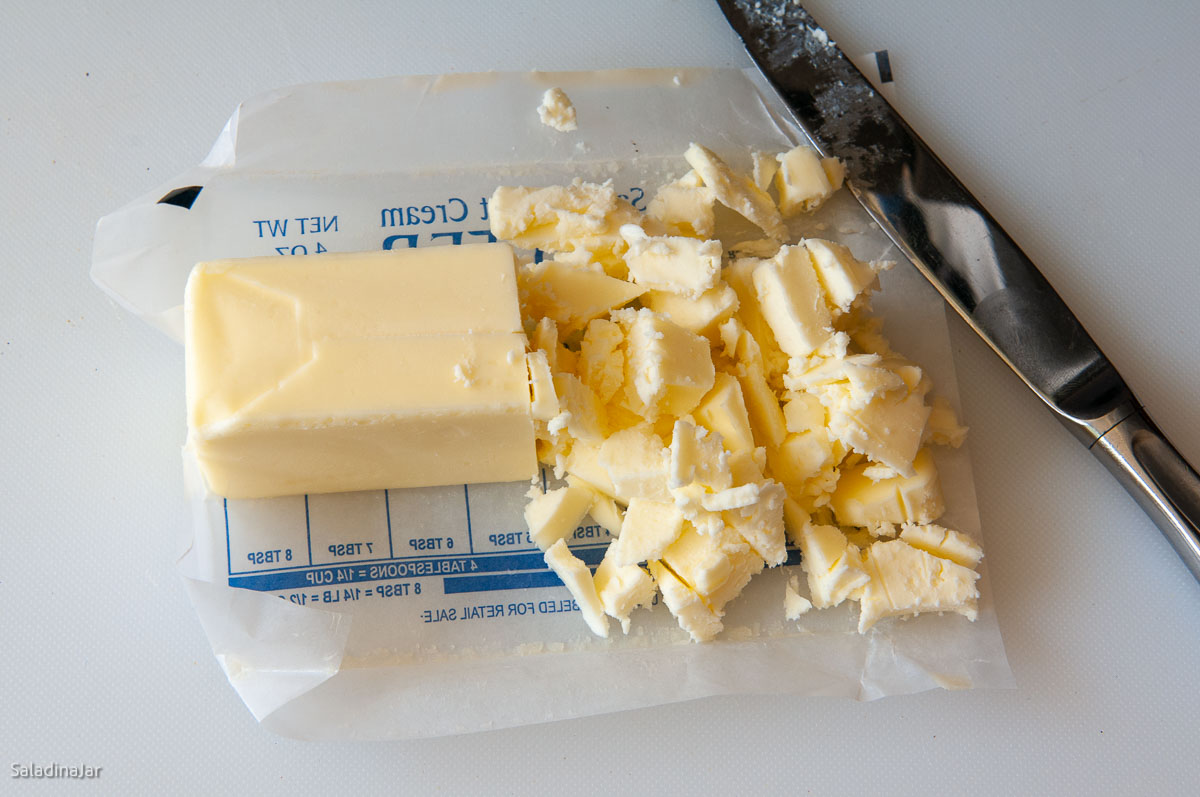 chopping butter on the wrapper with a table knife.