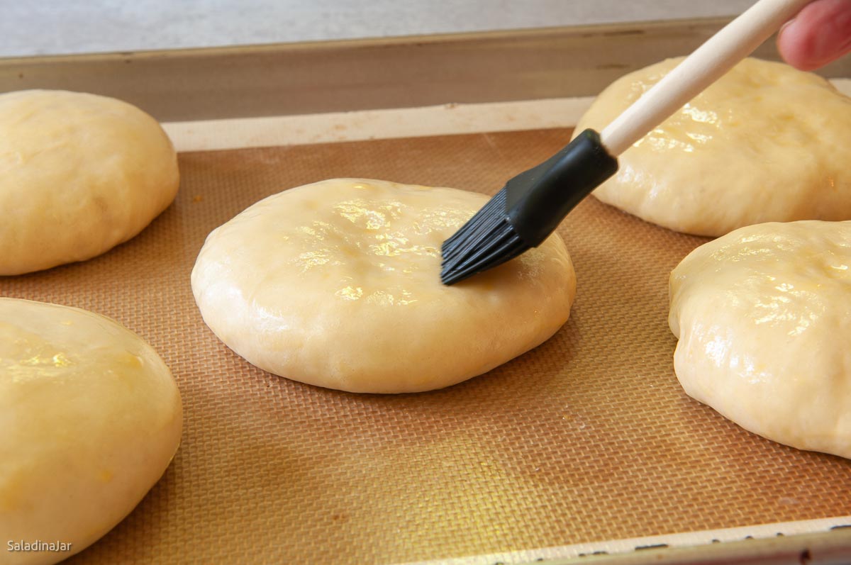 glazing the buns before baking.