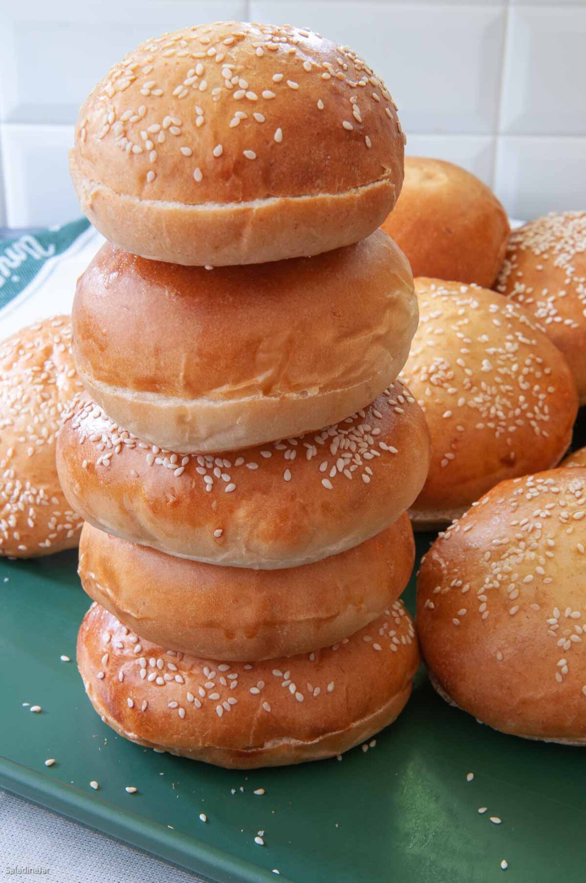 stack of burger buns--some with sesame seeds, others plain.