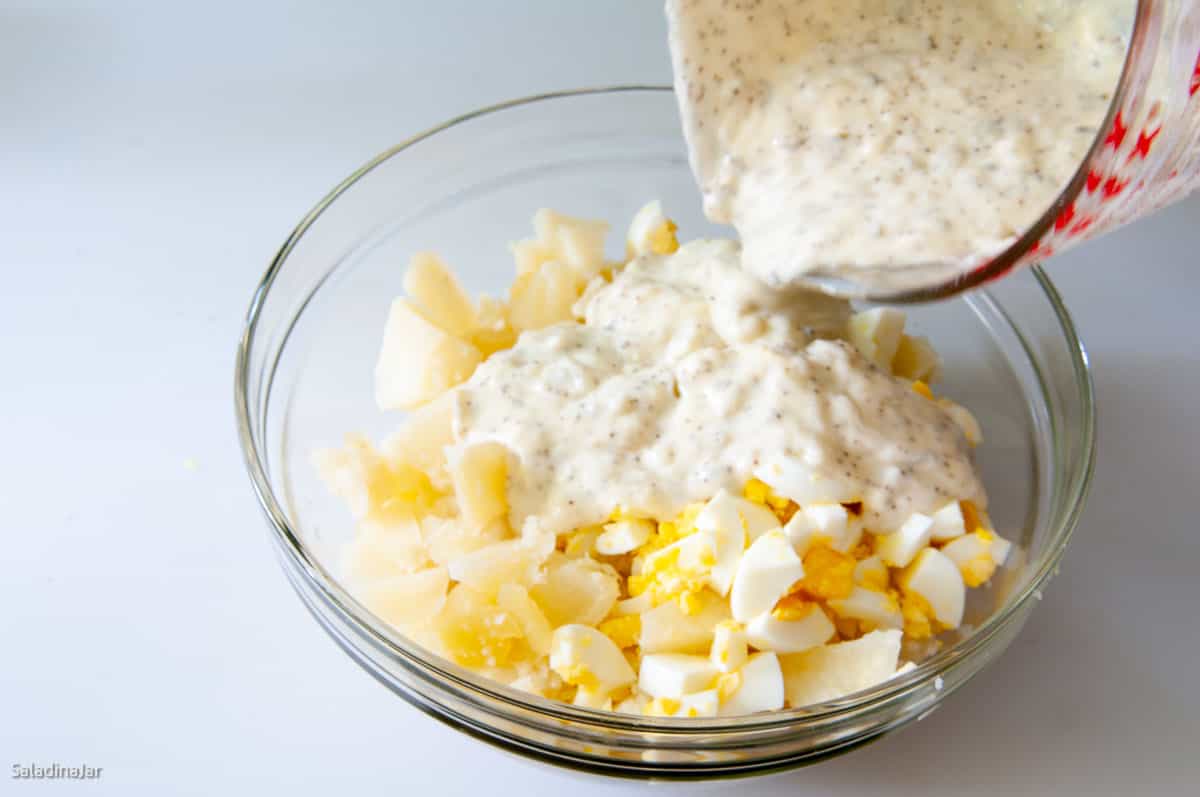 pouring cooked dressing over the potatoes and hard-boiled eggs