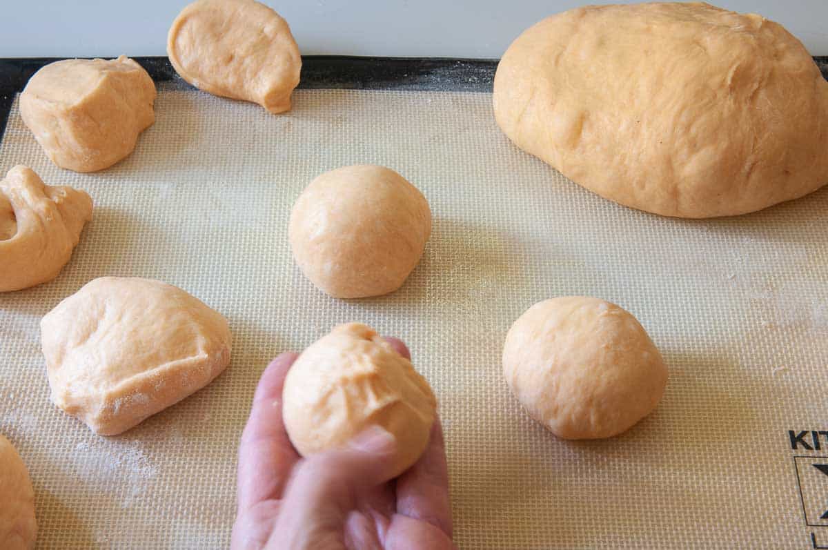 Making each dough portion into a ball by pinching the sides together underneath.
