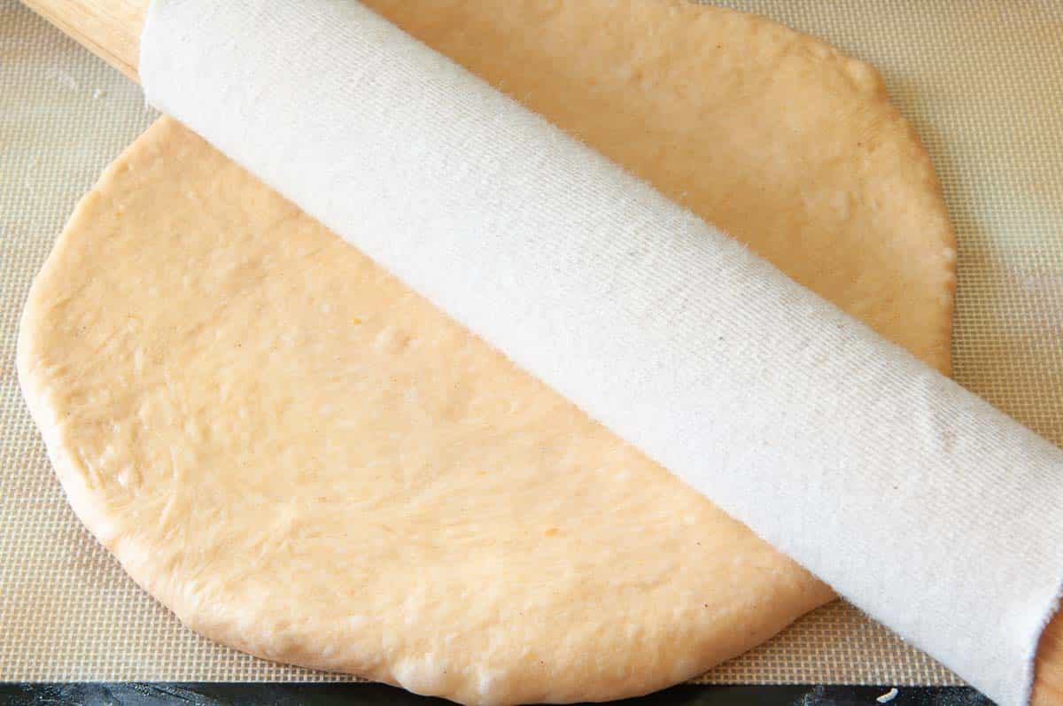 rolling dough into a circle with a rolling pin.