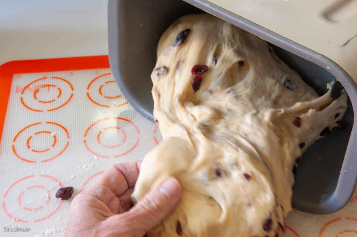 pulling dough out of the bread machine pan onto a lightly floured surface