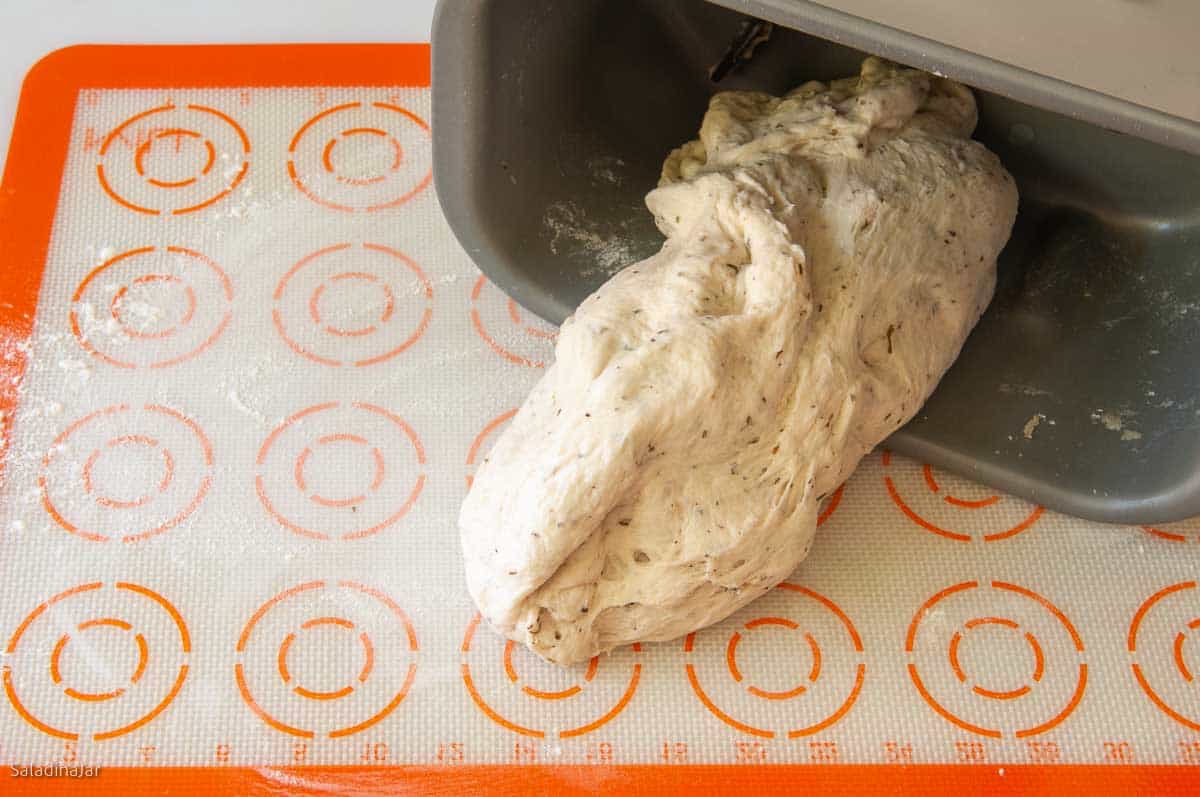 Pulling the dough out of the bread machine pan.