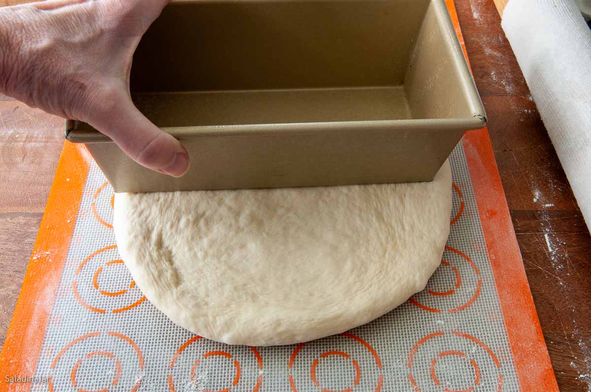 measuring the dough with a loaf pan to see if it is wide enough.