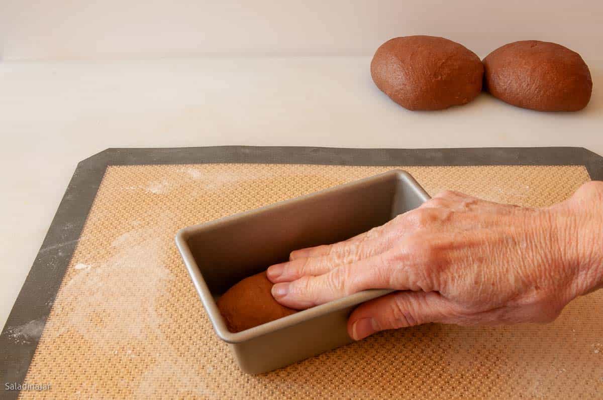 placing the dough into the pan and pressing down with your fingers.
