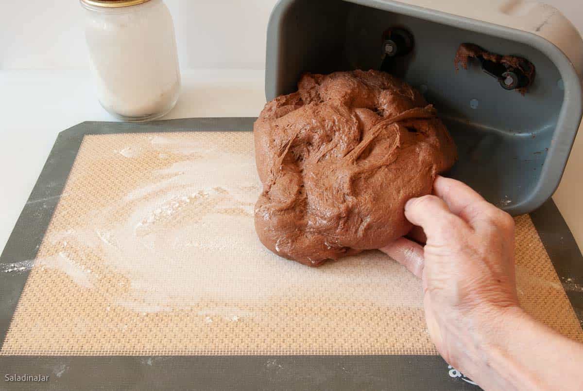 pulling the dough out of the bread machine pan.