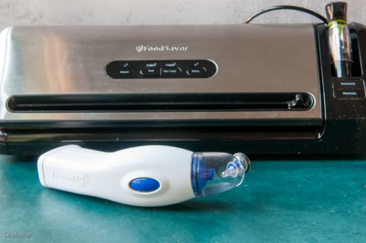 a countertop vacuum seal machine next to a handheld vacuum sealer to compare the size.