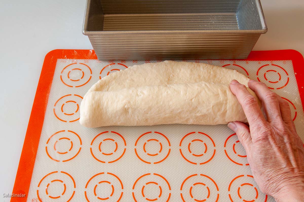 rolling the dough to make a loaf.