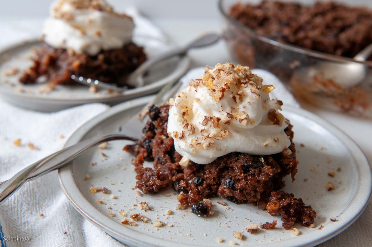 Bread crumb pudding on a plate covered with whipped cream and caramelized pecans