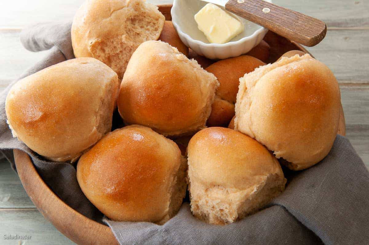 White Whole Wheat Bread Rolls in a bowl with butter on  the side.